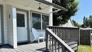Une terrasse en bois avec une rambarde, une porte et une fenêtre.