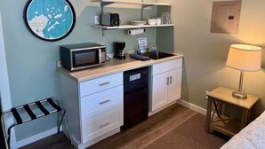 Une petite cuisine équipée d’un four à micro-ondes, d’une machine à café et d’une petite étagère.