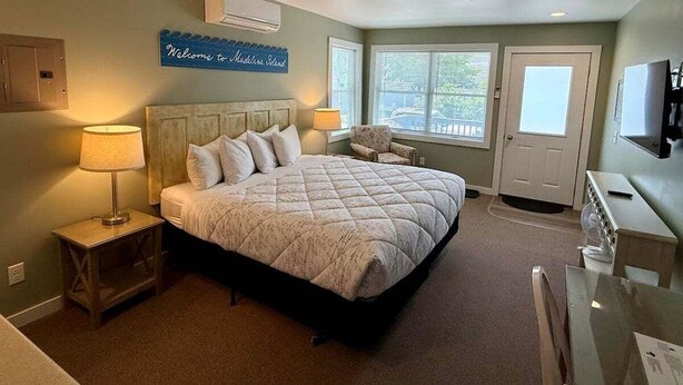 Une chambre à coucher avec un grand lit, des lampes de chevet, un fauteuil, un bureau et un téléviseur.