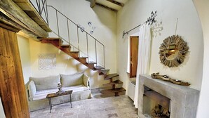 A rustic interior with a stone floor, a wooden staircase, a fireplace, and a sofa. - Villa Cenobio D: A characteristic and welcoming apartment that is part of an ancient country house made of stone, with Free WI-FI. (Umbertide)
