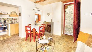 Un accogliente soggiorno con camino, una zona pranzo con sedie in legno e una cucina con schienale piastrellato.