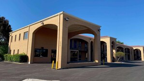 A building with a brick facade, multiple arched entrances, and a clear blue sky. - Homelodge Newnan (Newnan)