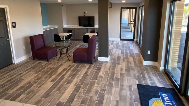 A hotel lobby with a seating area, a television, and a reception desk. - Homelodge Newnan (Newnan)