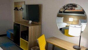 A hotel room with a TV, a mirror, a bed, a desk, and a chair. - Homelodge Newnan (Newnan)
