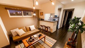 Een moderne woonkamer met een bank, salontafel en een keuken op de achtergrond.