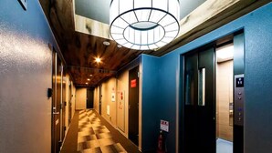 Een hotelgang met een geruit vloerkleed, houten plafond en blauwe wanden.