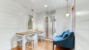 A room with a wooden dining table, two chairs, a blue sofa, and a mirror on the wall. - Discover The Sandy Moose: a spacious 4-bedroom retreat in serene Fennville, MI. (Fennville)