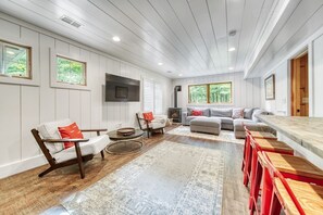 Cozy living area with a fireplace, sofa, and chairs, offering a comfortable seating space with views of the outdoors.