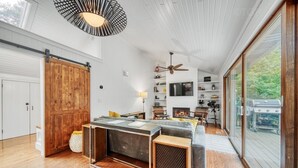 A spacious living area with a large sliding barn door, a fireplace, a ceiling fan, and a large sliding glass door to the outdoors. - Discover The Sandy Moose: a spacious 4-bedroom retreat in serene Fennville, MI. (Fennville)