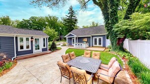 Un patio sul retro con tavolo e sedie, un'area barbecue e una zona salotto coperta.