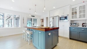 A modern kitchen with a central island, white cabinetry, and a blue accent wall.