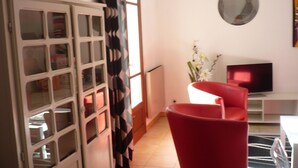 A room with a red chair, a television, and a white cabinet with glass doors. - Bas de Villa,piscine,calme,sécurisé, Ajaccio (Ajaccio)
