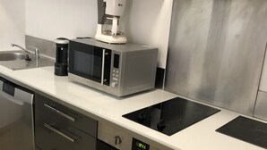 A modern kitchen with stainless steel appliances, including a microwave, coffee maker, and oven. - Bas de Villa,piscine,calme,sécurisé, Ajaccio (Ajaccio)