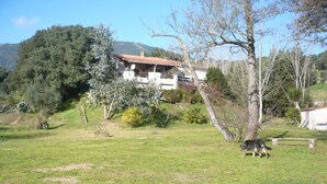 A rural house with a sloped roof, surrounded by a grassy field and trees. - Bas de Villa,piscine,calme,sécurisé, Ajaccio (Ajaccio)