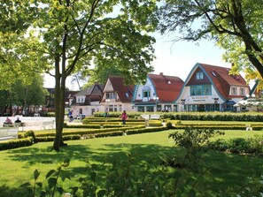Ein Park mit ordentlich geschnittenen Hecken und eine Reihe von Gebäuden im traditionellen europäischem Stil, mit sichtbarer Beschilderung.