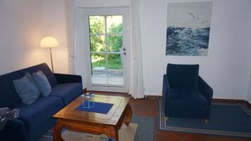 Ein Wohnzimmer mit Sofa, Sessel, Couchtisch und einem Gemälde an der Wand.
