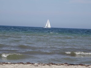A beach with waves and a sailboat in the distance. - FW Geltinger Birk - Luckow Georg Asmussen Haus (Pommerby)