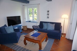A living room with two sofas, a coffee table, a TV, a window with curtains, and a lamp.