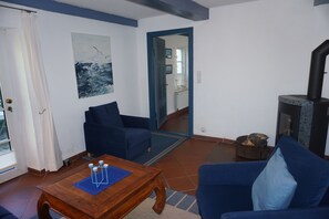 A living room with a blue sofa, a wooden coffee table, a fireplace, and a view through a doorway to another room. - FW Geltinger Birk - Luckow Georg Asmussen Haus (Pommerby)