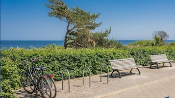A paved walkway with a bench and a bicycle parked on the side.