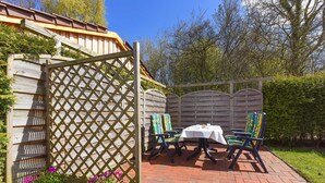 Een terras met houten omheining, een tafel en twee stoelen.