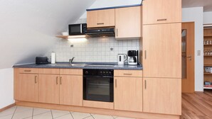 Een moderne keuken met houten kastjes, een zwarte oven, een magnetron en een koffiezetapparaat.