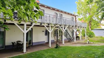 A two-story building with a balcony, outdoor seating, and a staircase leading to the upper level.