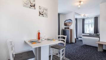 Een moderne, goed verlichte kamer met een eethoek, een zithoek en een keuken.