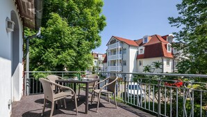 Un balcon doté de meubles en osier et offrant une vue sur les bâtiments voisins.