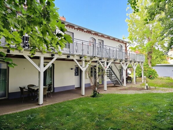 A two-story building with a balcony, outdoor seating, and a staircase leading to the upper level.