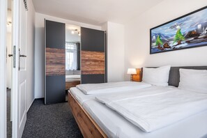Une chambre d’hôtel avec un lit, un tableau, une table de chevet et une porte donnant sur une autre pièce.