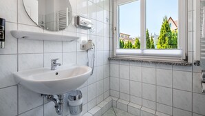 Une salle de bain moderne avec un lavabo blanc, un miroir et une fenêtre.
