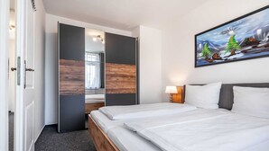 Et hotelværelse med en seng, et billede, et natbord og en dør, der fører til et andet rum.