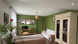 Un salon comprenant un canapé, un téléviseur, un meuble et un grand miroir.