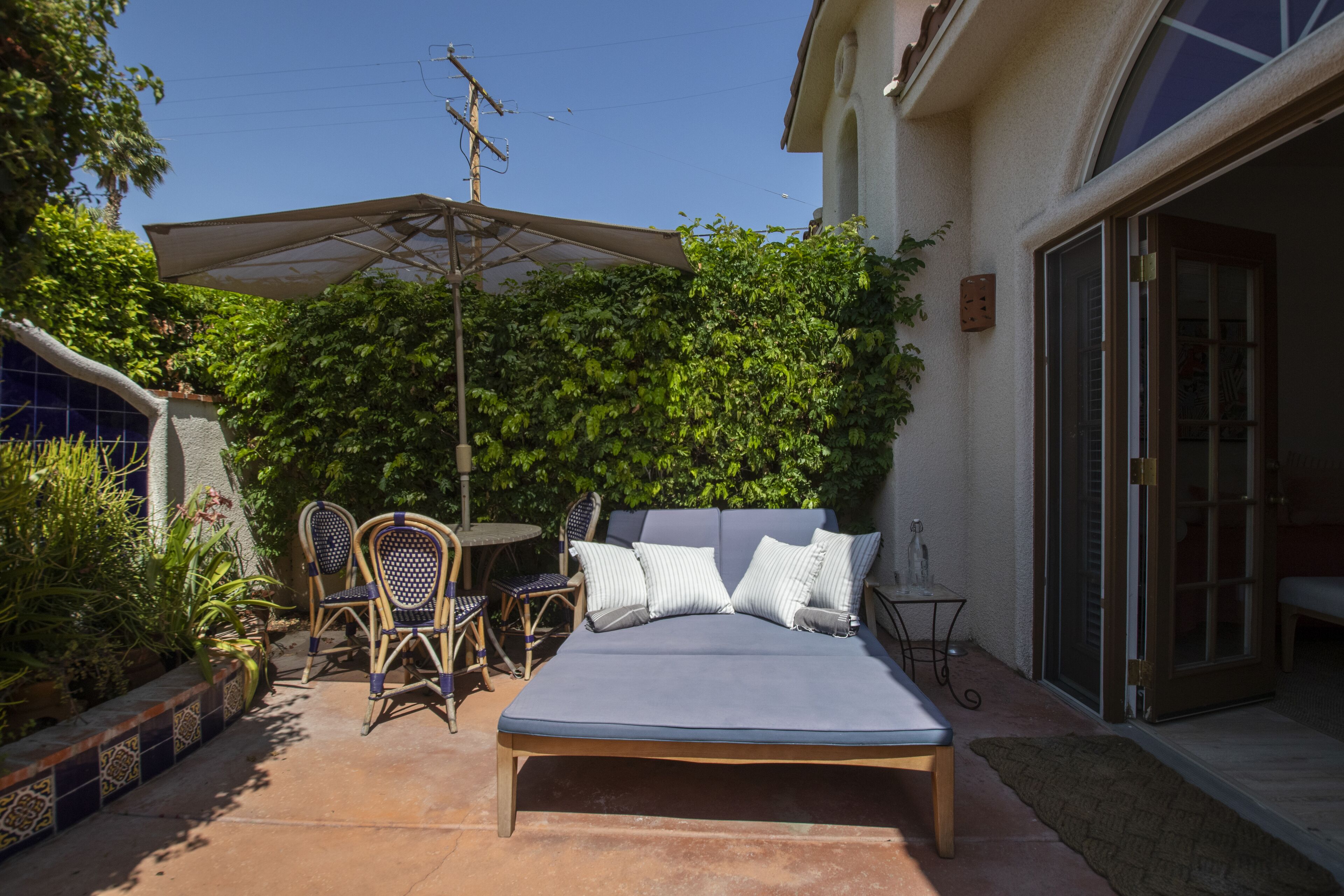 Eine Terrasse mit Bett, Stühlen und Tisch.