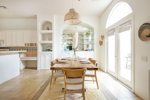 Una cocina amplia con armarios blancos, una mesa de comedor de madera y un ventanal que proporciona luz natural.