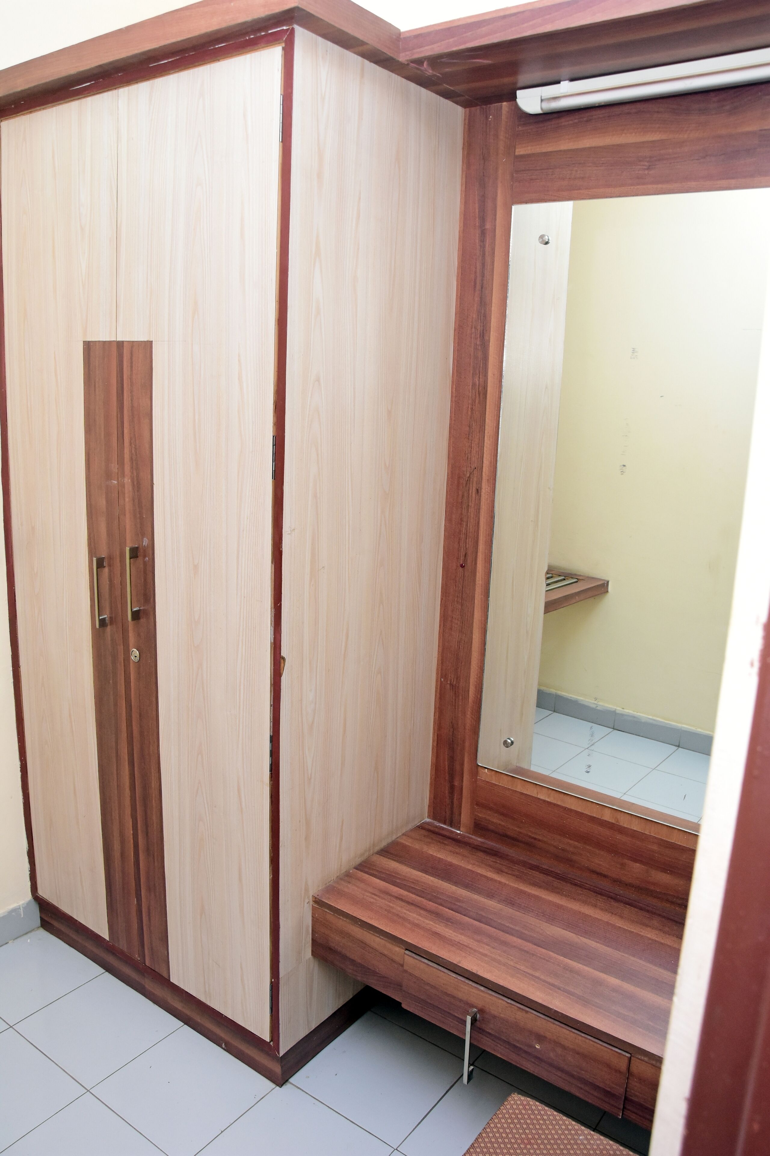Un armario de madera con espejo y un pequeño banco de madera.
