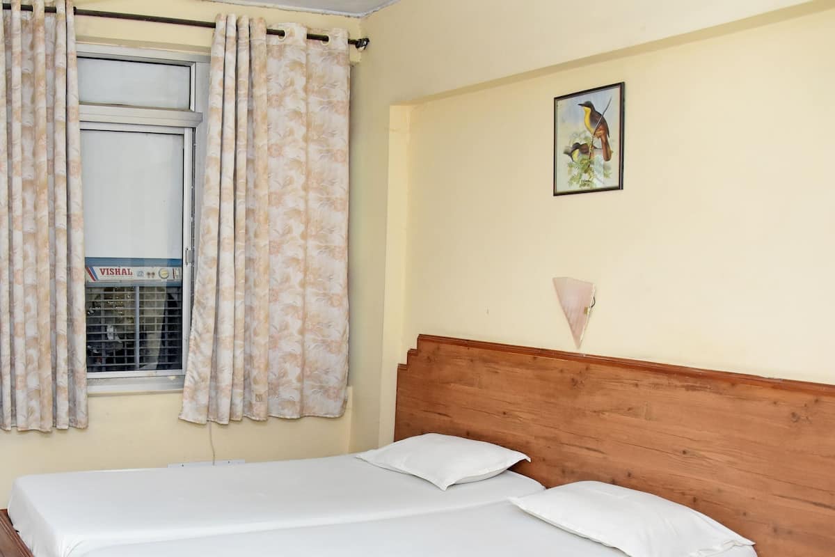 Cama doble con ropa blanca, cabecera de madera, ventana con cortinas florales y un cuadro colgado en la pared.