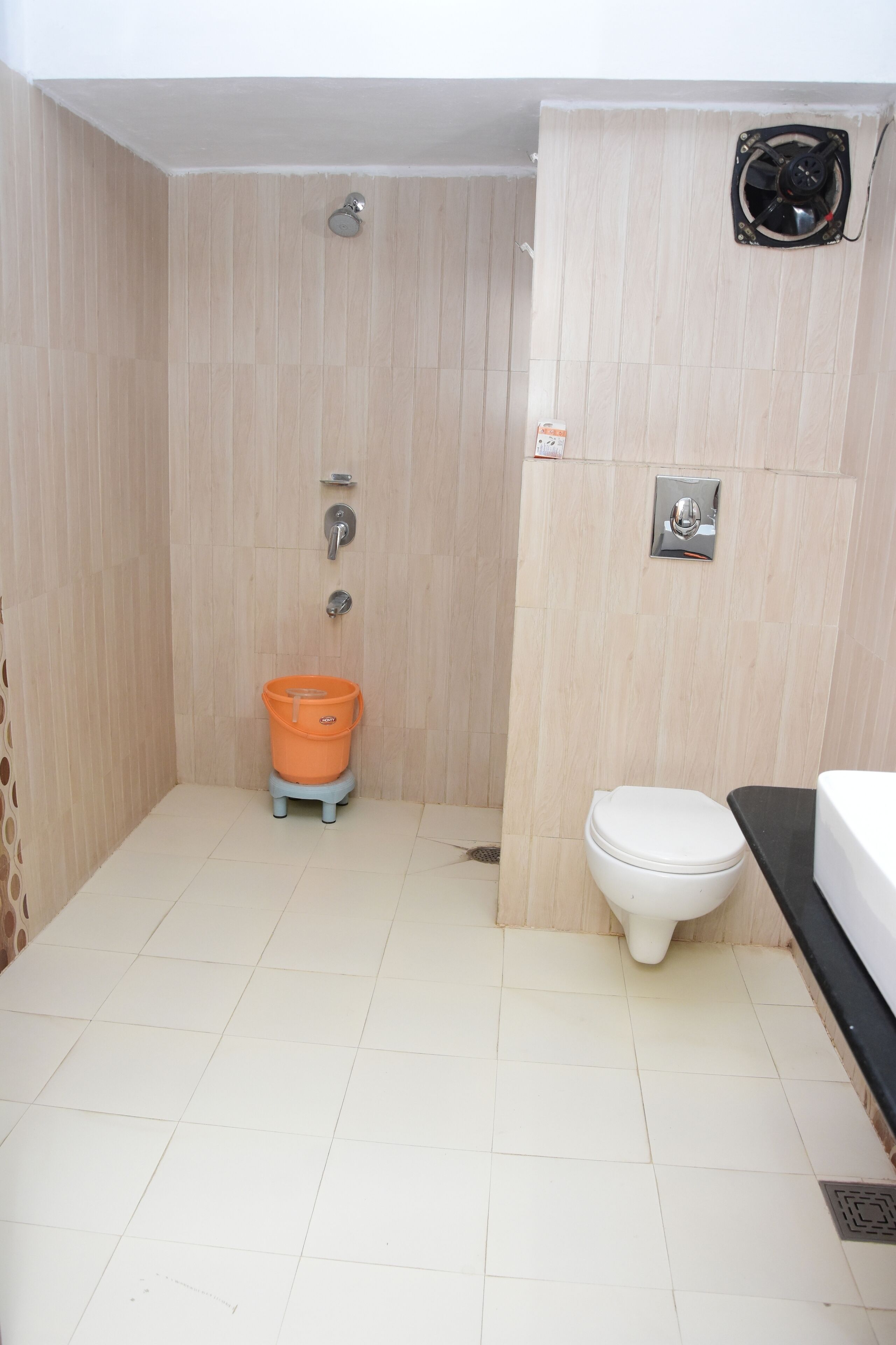 Een kleine badkamer met tegels, voorzien van douche, toilet en wastafel.