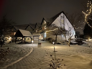 A hotel with a snow-covered landscape, a covered outdoor seating area, and a sign indicating the hotel name.