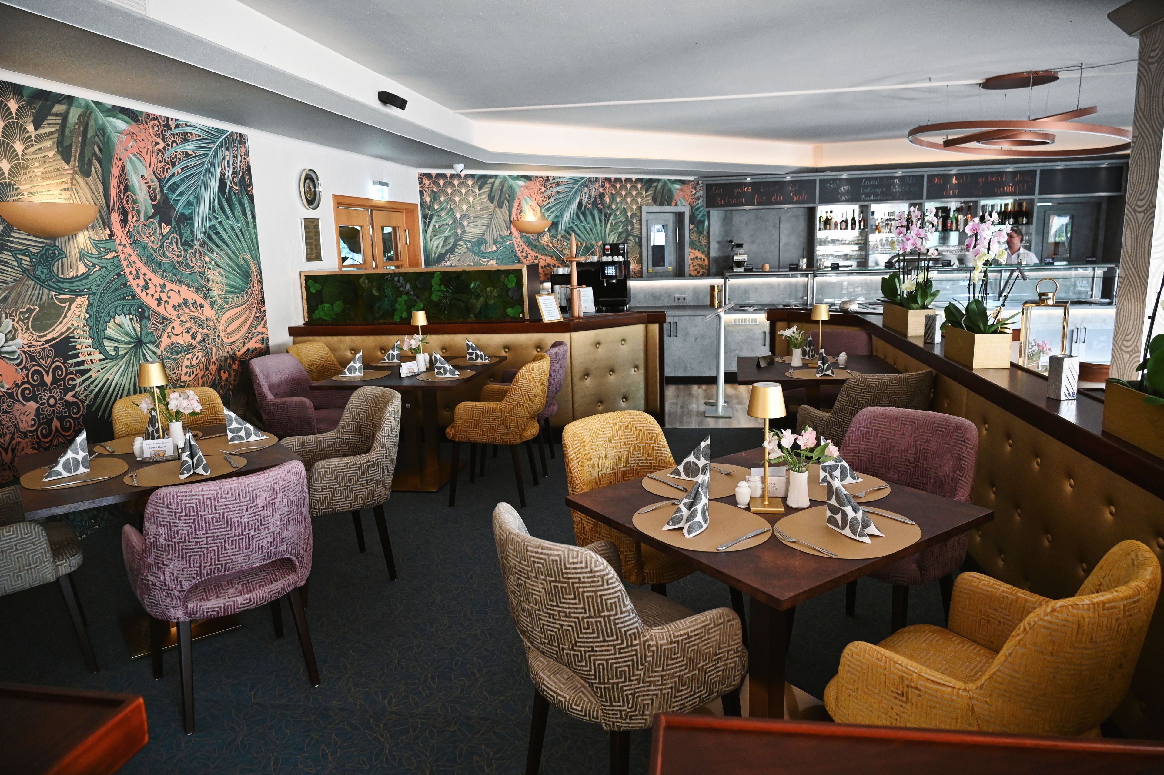 A restaurant with a bar area, seating with patterned chairs, a counter with a menu, and a decorative wall.