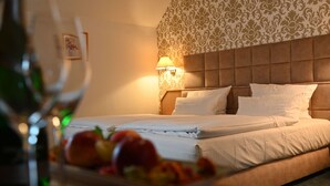 Une chambre d’hôtel avec un lit, une lampe fixée au mur et une assiette de fruits sur la table de chevet.