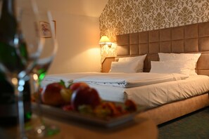 Une chambre d’hôtel avec un lit, une lampe fixée au mur et une assiette de fruits sur la table de chevet.