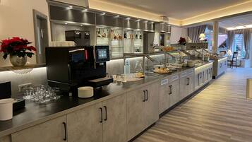 Een moderne hotelbar met een koffieapparaat, drinkglazen en diverse flessen.