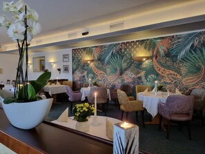 A restaurant with tables, chairs, candles, and a peacock-themed wall. - Duroc Comfort Double Room - Marschall DuRoc Hotel**** (Markersdorf)
