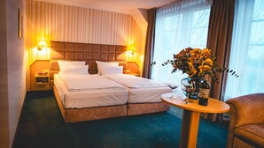 Habitació d'hotel amb un llit doble, dues taules de nit, una taula petita rodona amb una ampolla i un got, i una cadira.