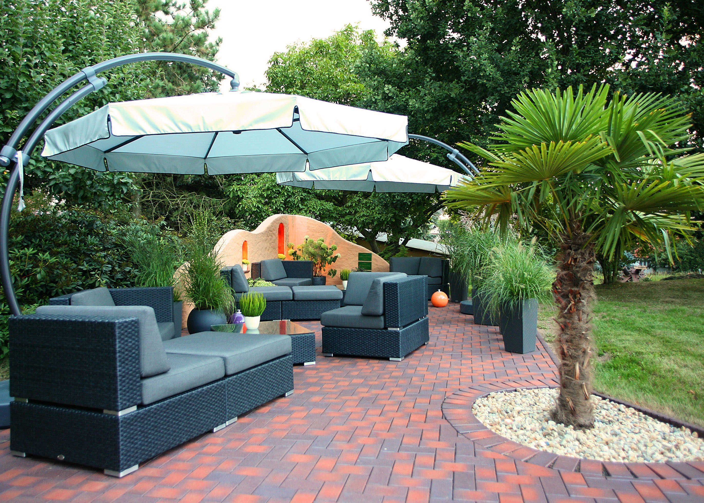 Un espace patio aménagé avec du mobilier d’extérieur, un coin salon couvert et un palmier.