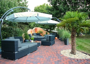 A patio area with outdoor furniture, a covered seating area, and a palm tree. - Duroc Comfort Double Room - Marschall DuRoc Hotel**** (Markersdorf)