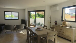 A modern kitchen with a dining area, wooden furniture, and a view through the sliding glass doors.