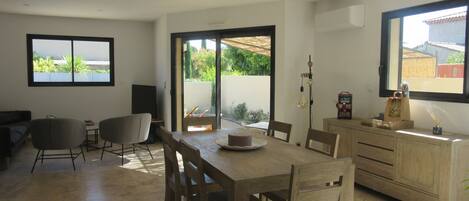 A modern kitchen with a dining area, wooden furniture, and a view through the sliding glass doors.